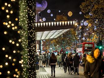 shoppers shopping on Oxford Street, London, with Christmas lights shown